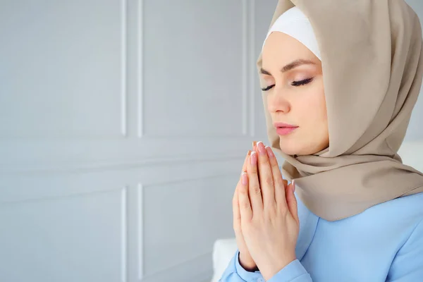 Bej başörtüsü ve gözleri kapalı dua geleneksel giysiler genç Müslüman kadın Portresi — Stok fotoğraf
