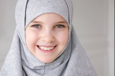Türbangenç müslüman genç kız utangaç kameraya bakarak ve gülümseyerek.