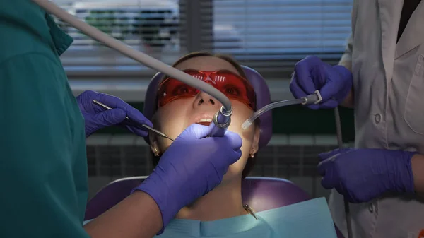 Tandarts is het verzorgen van patiënten tand met behulp van elektrische tandheelkundige borstel. Dames portret in Dental Chair. — Stockfoto