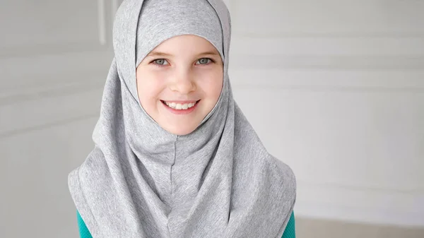 Ung muslimsk tonårs flicka i hijab blygt tittar på kamera och leende. — Stockfoto