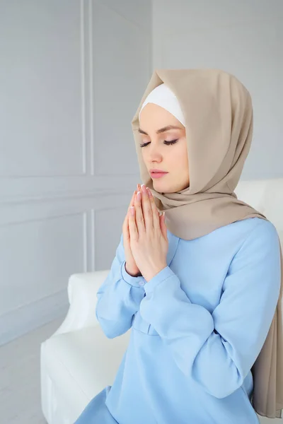 Young muslim woman in beige hijab and traditional clothes praying with eyes closed for Allah, muslim God — 스톡 사진