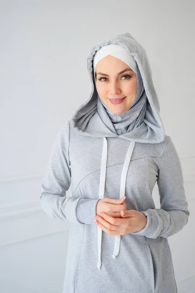 Portrait of young Muslim woman in gray hijab and national fitness dress at home — Stok Foto