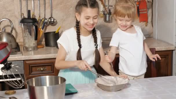 Twee meisjes zusters mengen ingrediënten in een kom. — Stockvideo