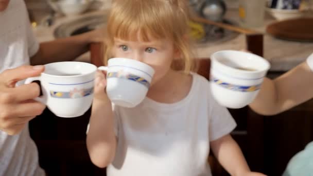 Niña tintinea tazas de té con su familia . — Vídeos de Stock