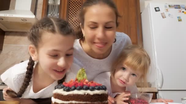 Feliz mamá e hijas están oliendo pastel de chocolate cocido con bayas . — Vídeos de Stock