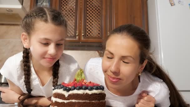Feliz mamá y su hija están oliendo pastel de chocolate cocido con bayas . — Vídeo de stock