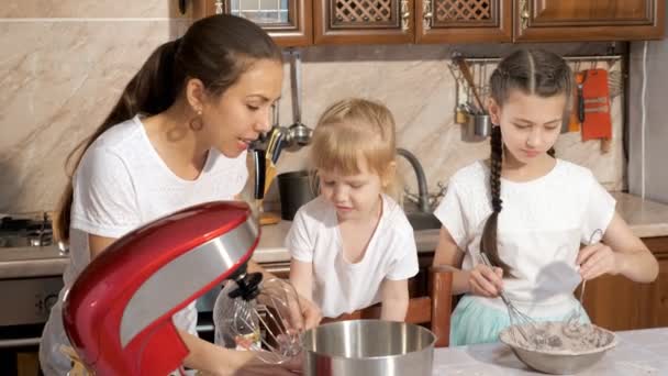 Máma vaří se svými dvěma dcerami v kuchyni. — Stock video