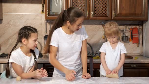 Мама готовит пирог из теста с двумя дочерьми на кухне. . — стоковое видео