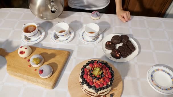 Mujeres manos vierten té en tazas en casa sobre la mesa con dulces para celebrar el cumpleaños . — Vídeos de Stock