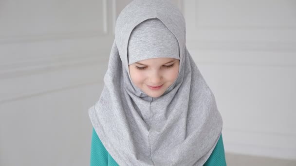 ヒジャーブの若いイスラム教徒の十代の女の子は恥ずかしがり屋でカメラを見て、笑顔. — ストック動画