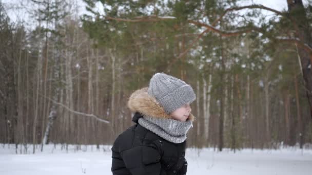 Bambino ragazzo sta gettando un po 'di neve in aria godendo la stagione fredda al rallentatore . — Video Stock