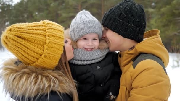 Mama und Papa kuscheln und küssen ihren kleinen Sohn im Winterpark. — Stockvideo