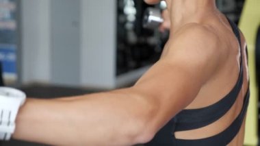 Spor giyim sportif tanınmaz kadın spor salonunda dumbbells ile yan ellerini yayılır.
