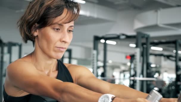 Retrato de mulher está fazendo exercícios para os músculos da coluna vertebral na máquina de remo . — Vídeo de Stock