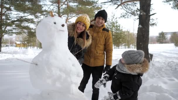 Bonne famille maman, papa et fils font un bonhomme de neige dans le parc de la ville d'hiver . — Video