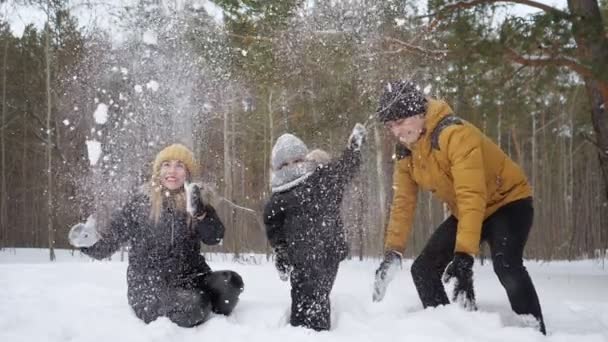 Mamãe e papai estão jogando uma neve fazendo uma queda de neve para seu filho em câmera lenta . — Vídeo de Stock