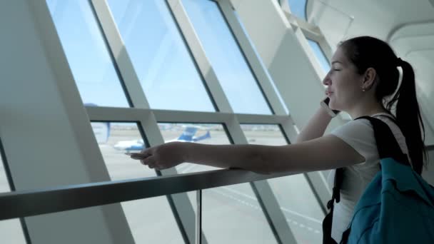 Junge Frau telefoniert im Flughafen-Terminal in Flugzone. — Stockvideo