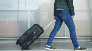 Kadın bavul, closeup bacaklar taşıyan modern havaalanı terminalinde yürüyor.