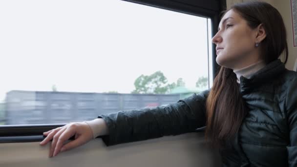 Uma mulher no comboio. Ela está sentada e olhando pela janela . — Vídeo de Stock