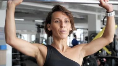 Kadın jimnastik salonunda kafasına kaldırarak halter ile reps egzersiz seti yapıyor.