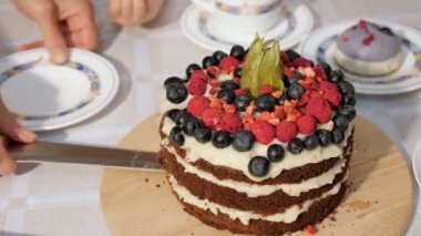 Kadın doğum günü ev yapımı çikolatalı kek parçası dilimler ve plaka üzerine koyar, eller closeup.