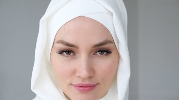 Mulher muçulmana atraente vestindo hijab está olhando para a câmera e sorrindo . — Vídeo de Stock