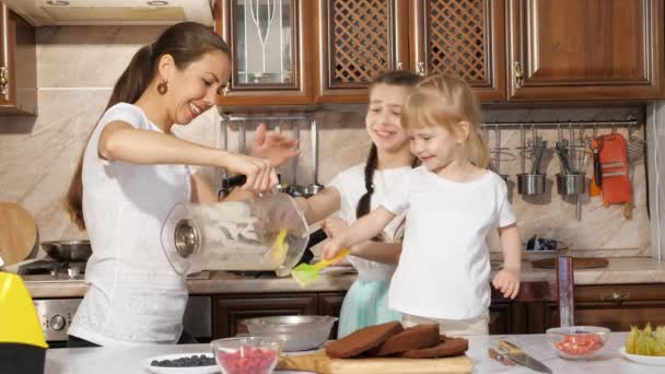 Familia, mamá e hijas están cocinando crema para pastel y verter en un tazón de licuadora . — Vídeo de stock