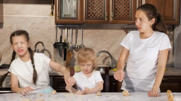 Mamma e figlie si gettano la farina mentre cucinano in cucina . — Video Stock