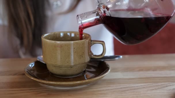 Chica vertiendo té rojo en la taza en la cafetería — Vídeos de Stock