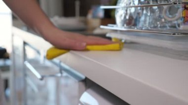 Kadın sarı bez kullanarak mutfak masası siler, el closeup.