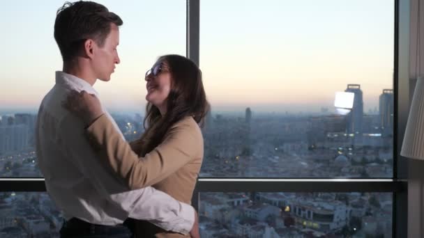 Par, man och kvinna dansar nära panoramafönstret med utsikt över staden. — Stockvideo