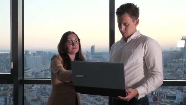 Kollegen diskutieren im Büro am Panoramafenster über Arbeitszeiten. — Stockvideo