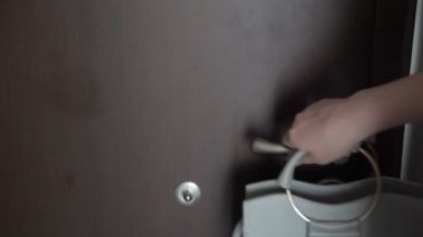Bavullu ve el çantası olan kadın kiralık dairelerden ayrılıyor, elleri kapatıyor.