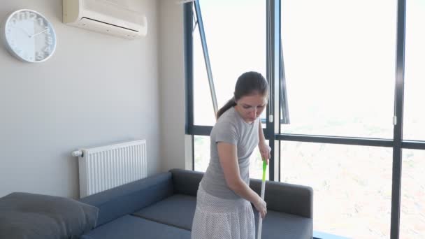 Jovem mulher limpa chão na sala de estar usando esfregona . — Vídeo de Stock