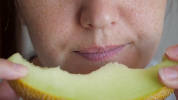 Femme avec des taches de rousseur sur le visage est mordant et mâcher tranche de melon, bouche gros plan . — Video