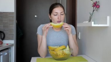 Kadın küçük mutfakta masada oturan kavun yeme zevk.