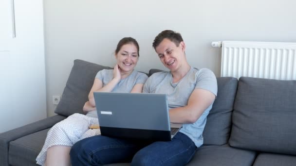 Man och kvinna tittar komedi film på laptop och skrattar sitter på soffan. — Stockvideo