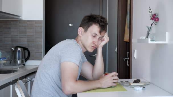 Álmos ember, amelynek egy csésze teát ül a kis konyhában bérleti lakás nyaralni. — Stock videók
