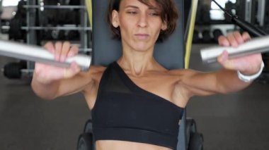 Sportif kadın eğitim makinesinde silah kasları için egzersizyapıyor.