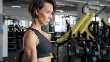 Sportif olgun kadın spor salonunda dumbbells ile pazı egzersiz yapıyor.