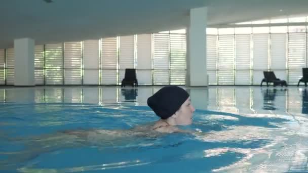 Mujer joven está nadando estilo libre en la piscina, vista lateral . — Vídeo de stock