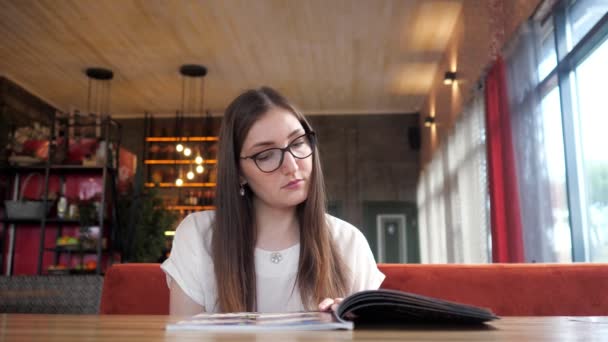 Chica leyendo el menú en la cafetería — Vídeos de Stock