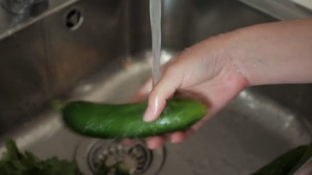 Mujer está lavando tomates y pepinos para ensalada en fregadero de cocina, manos de cerca . — Vídeo de stock