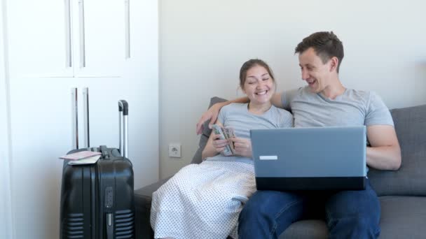 Homme et femme vont au voyage attraper l'argent assis sur le canapé à la maison . — Video