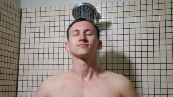 Portrait of young man is taking a shower combing his hairs with hands. — Stock Video