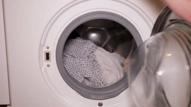 Kadın çamaşır yapar ve evde çamaşır makinesi bir giysi alır.