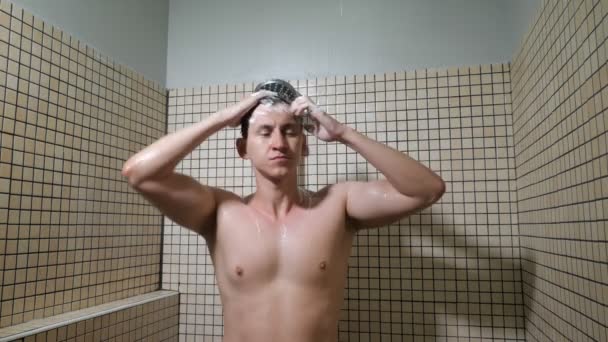 Portrait of young man in playful mood is taking a shower and washing his head. — Stockvideo