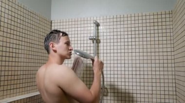 Adam bir duş alarak bir mikrofon olarak duş kullanarak şarkı.