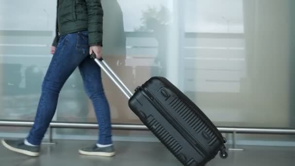 Vrouw loopt in moderne luchthaven terminal met koffer, close-up benen. — Stockvideo