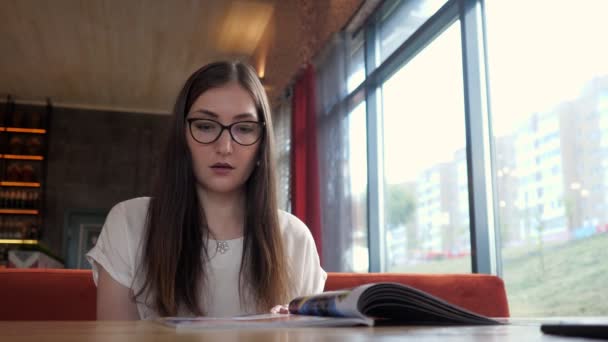 Chica en la cafetería comer, mirando el menú en la cafetería — Vídeos de Stock